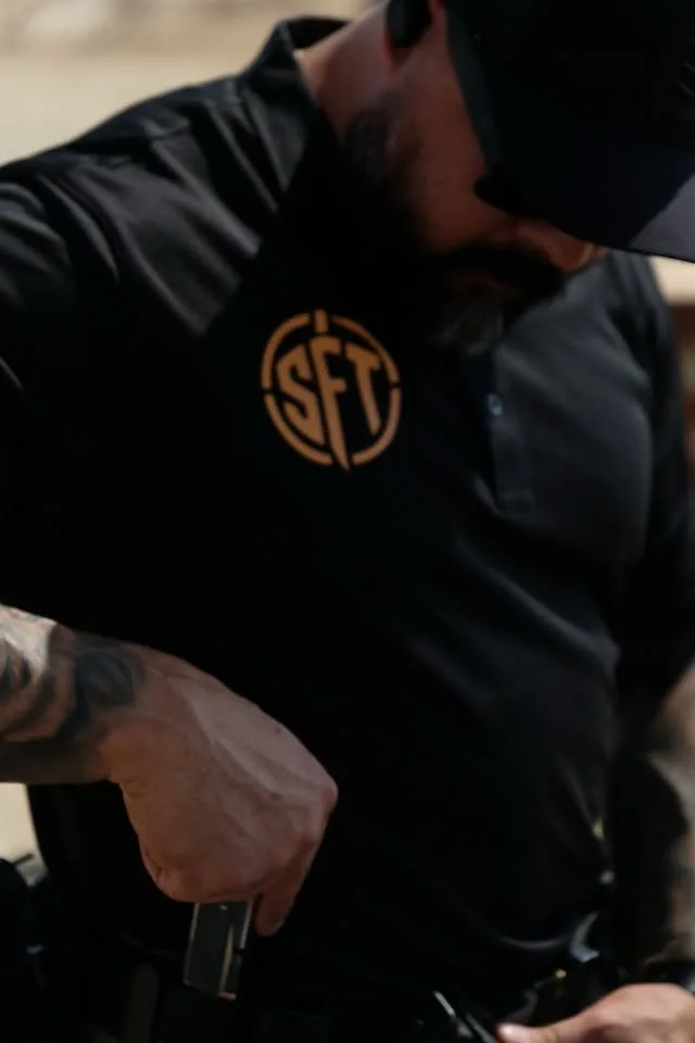 Close-up of a student drawing a duty handgun from the holster, magazine in hand, during pre-course firearms prep.
