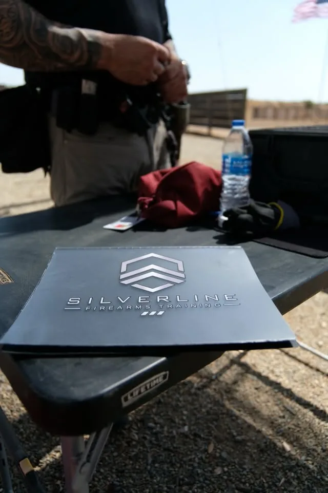 A Silverline Firearms Training instructor rigging a duty belt beside the range table before a qualification.